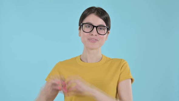 Attractive Young Woman Showing Heart Sign on Purple Background