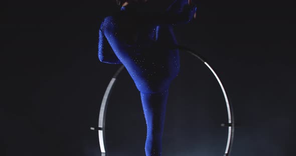 Professional Gymnast is Performing in Low Lighting Doing a Split in a Hoop