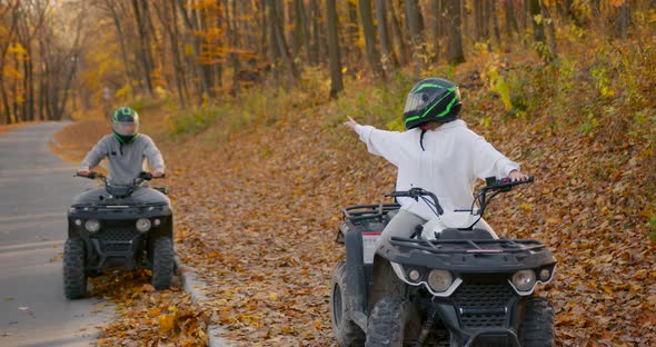 A Young Couple Rides an ATV Offroad in the Autumn Forest