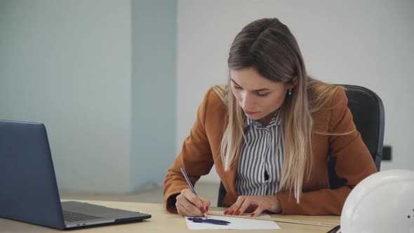 Young Woman Accountant Working with Financial Document Sitting at Table in Office Room