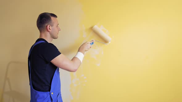 Young worker painting wall in room. Repair, building and home concept.