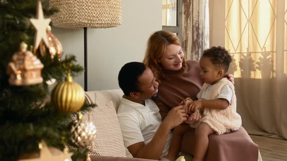 Parents Play with Their Child Near the Christmas Tree