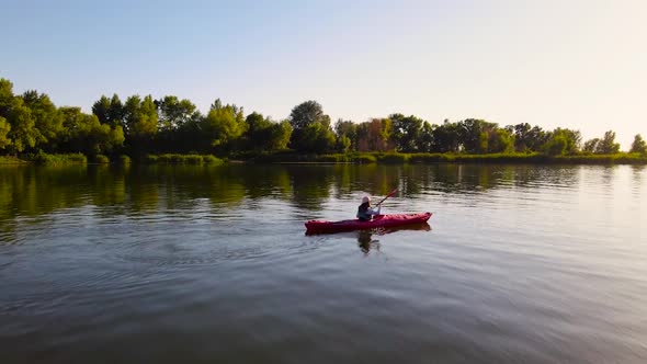 Young female traveler floats in kayak on river in summer.