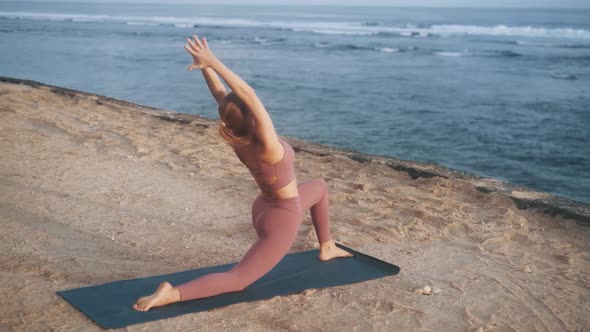 Woman Does Yoga Exercises and Stretches at Morning on Mat at Beach Slow Motion