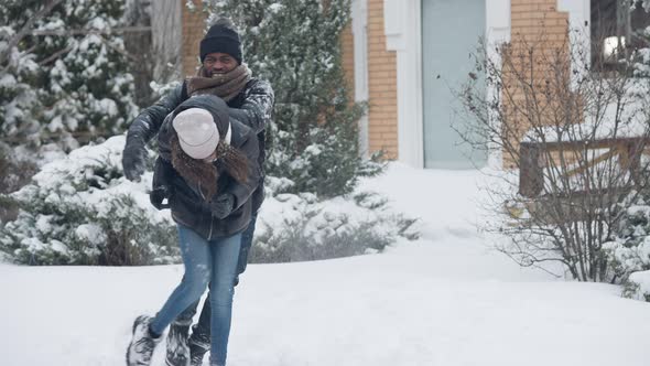 Joyful African American Man and Teen Girl Having Fun with Snowball Fight Outdoors Falling in White