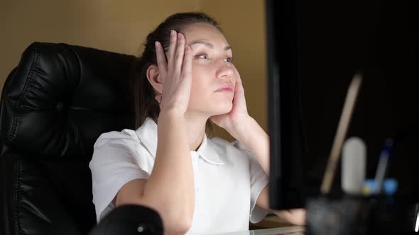 girl looks tiredly at the monitor, sitting at work at night, the camera moves