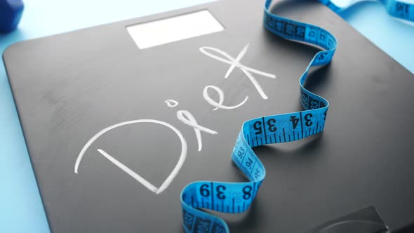 Diet Text on Weight Scale with Dumbbell and Measurement Tape on Blue
