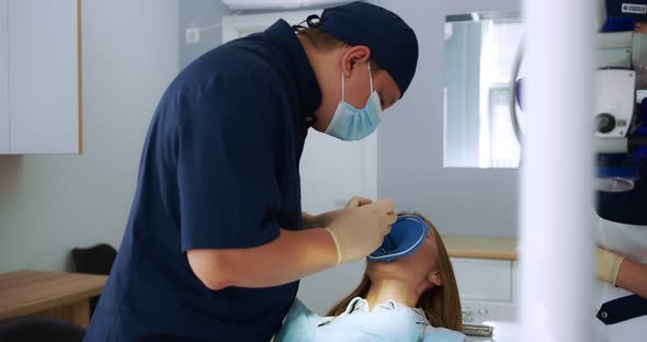 AA Male Dentist Performs the Procedure of Applying a Cofferdam to Patient