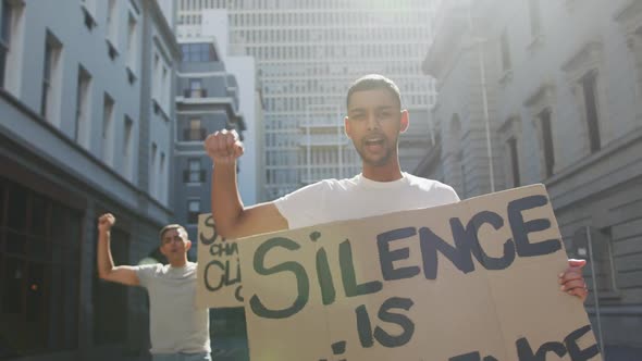 Two mixed race men on a protest march holding placards raising hands and shouting