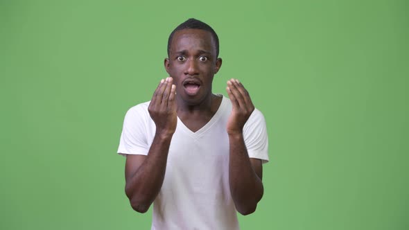 Young African Man Looking Shocked Against Green Background