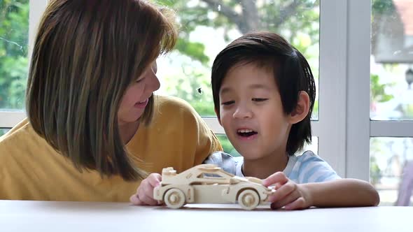 Asian Mother And Son Playing Wood Toy Car Together