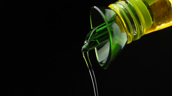 Slow motion shot of extra virgin olive oil being poured out a clear glass bottle