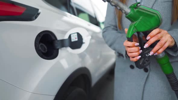 Woman Fills Petrol Into Her Car at a Gas Station Close-up