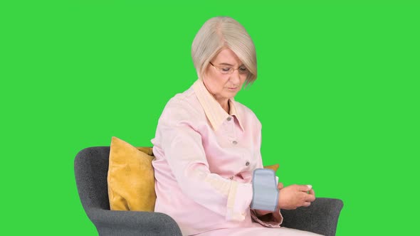 Aged Woman Measuring Blood Pressure Reaction on a High or Low Pressure on a Green Screen Chroma Key