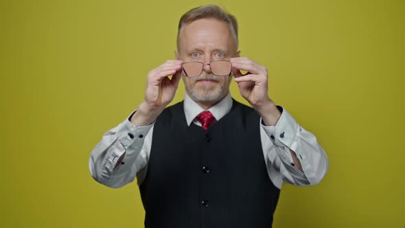 Senior man holding eyeglasses in front of himself