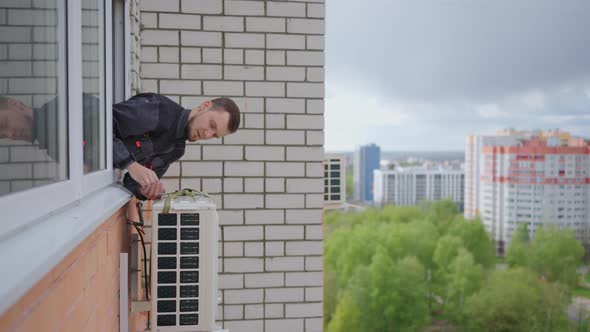 A Man at High Altitude Installs Air Conditioning