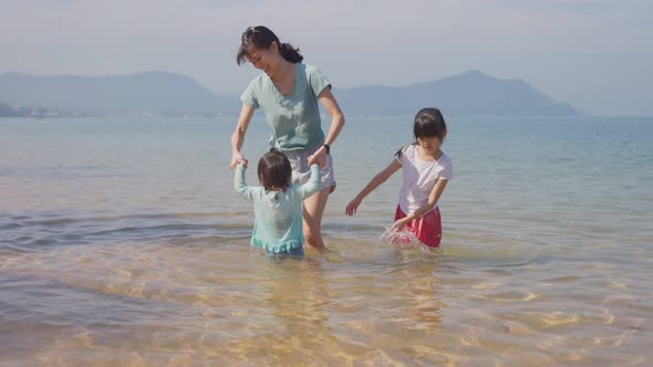 Happy Asian family, Mother playing and having fun with children on the beach during holiday vacation