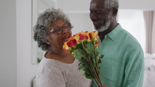 A senior African American man offering flowers to his wife