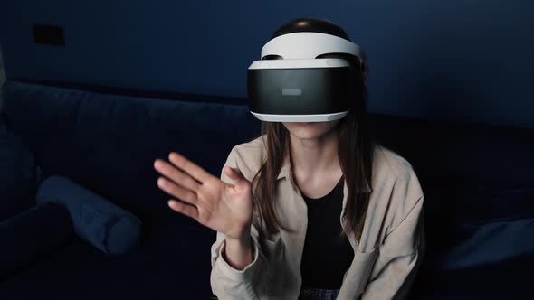 Young Caucasian Woman Wearing VR Helmet Making Hands Gesture at Home. Attractive Woman Enjoying