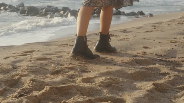 Closeup Cinematic Shot of Woman Feet in Boots Walking on the Beach at Sunset or Sunrise