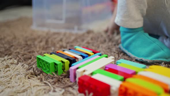 Children's Hands on the Carpet Build From the Blocks of the Constructor Fold Into the House the Game