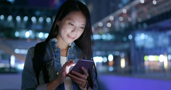 Woman work on mobile phone in city at night