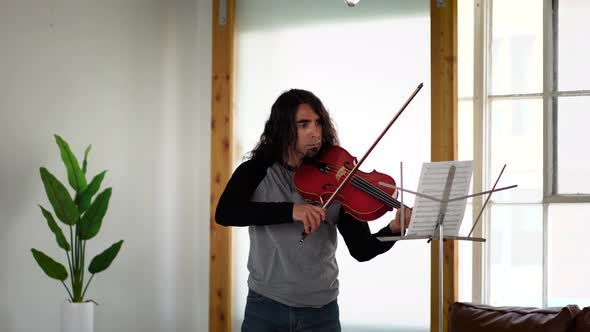 Medium shot of long hair hispanic male musician in grey and black long sleeve shirt performing song