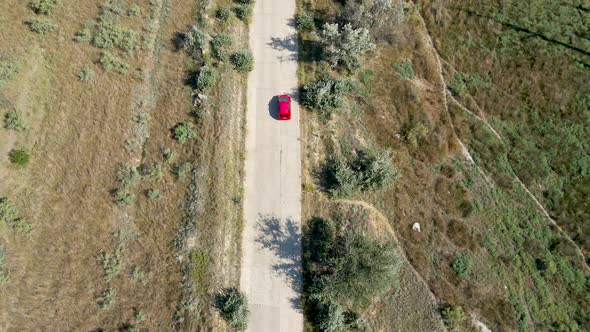 a Red Passenger Car Drives on a Shroud on a Concrete Road