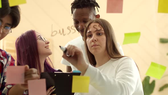 Team of different nationalities work together on a project looking at a paper tablet and drawing on