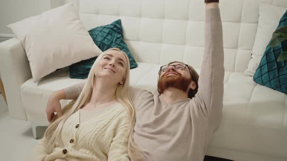 Content Caucasian Couple Celebrating Valentine's Day Laying on the Floor Looking Up and Smiling