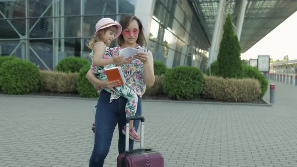 Mother and Daughter Near Airport. Woman Hold Passports and Tickets in Hand. Child and Mom Vacation