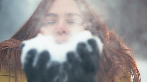 Young Girl Walking in the Woods Blowing a Handful of Snow on Camera