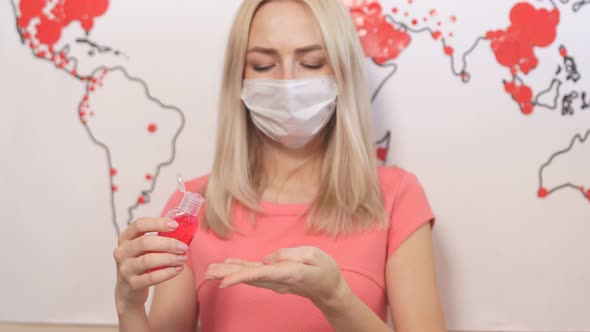 Concerned Girl in Medical Mask Uses Antiseptic, Stands in Background of Map the Spread of Virus