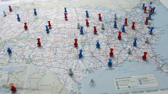 Camera pan revealing red white and blue pins placed marking cities on a US map.