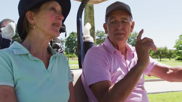 Caucasian senior couple driving a golf cart with clubs on the back at golf course