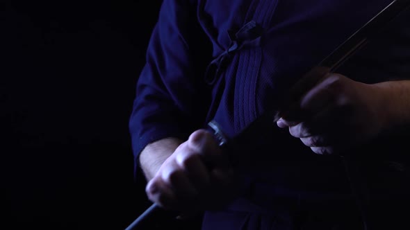 A Close-up Shot of a Ninja Man's Hand Holding a Sword and Raising It.