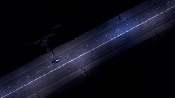 Zoom in at road int the night. Aerial shot. Cars passing. Street lights close up. Drone