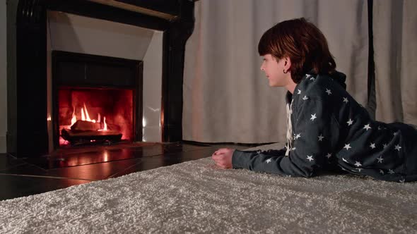 Handsome Young Boy Sit in Front of Fireplace Looking at Fire