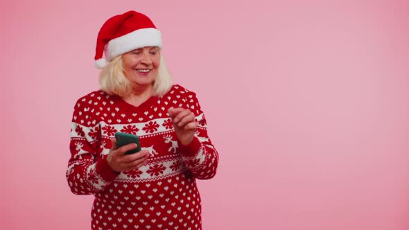 Grandmother Santa Christmas Sweater with Mobile Phone Showing Pointing Empty Place Advertising Area