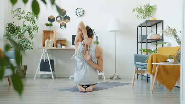 Slow Motion of Guy Doing Yoga Exercise Stretching Arms Muscles Indoors at Home
