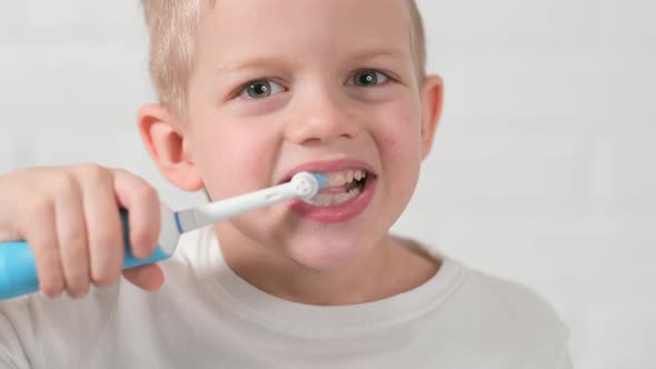 Portrait Happy Smiling Child Kid Boy Brushing Teeth with Electric Toothbrush on White Brick