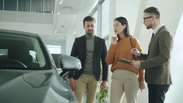 Young Family Purchasing Automobile in Car Dealership Talking To Sales Manager