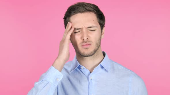 Young Man with Headache on Pink Background