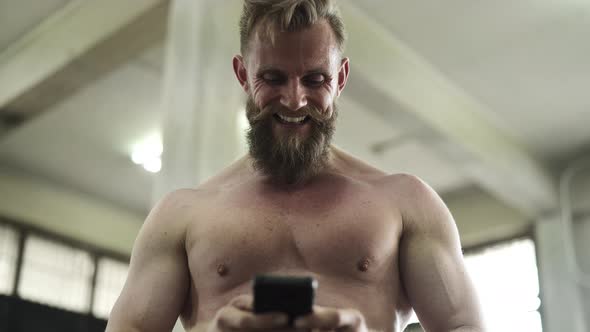 Muscular Man Laughing While Texting