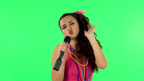 Attractive Girl Sings Into a Microphone and Moves To the Beat of Music