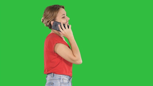 Blonde woman walking and talking on the phone on a Green