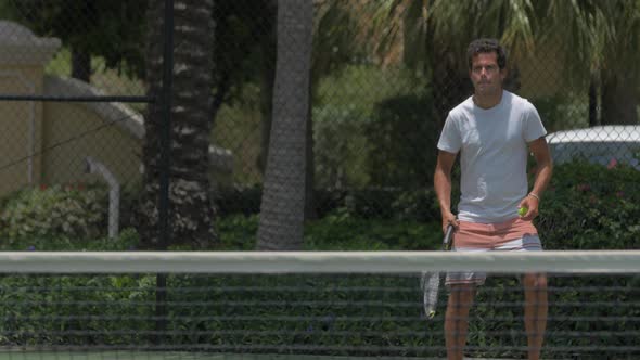 A boyfriend playing tennis against his girlfriend while on vacation.