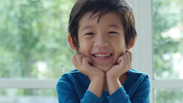 Cute Asian Child Resting Chins On Hands On Wood Table