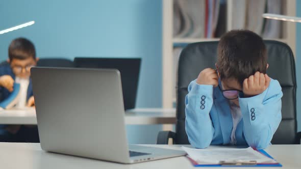 Tired and Stressed Little Businessman Working on Laptop at Office.