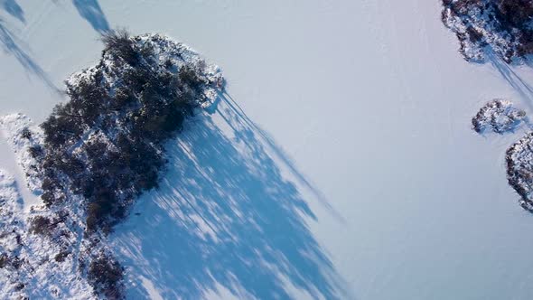 Aerial birdseye view of snowy bog landscape with frozen lakes in sunny winter day, Dunika peat bog (